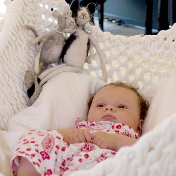 Baby liegt auf der Babymatratze für den Babyschwinger